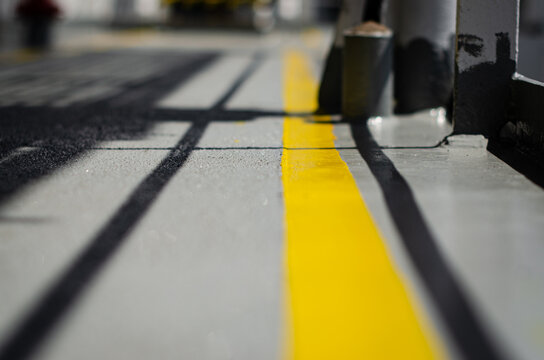 Close-up view of the exterior deck surface on board an offshore support vessel, featuring an anti-slip coating and clearly defined yellow deck markings
