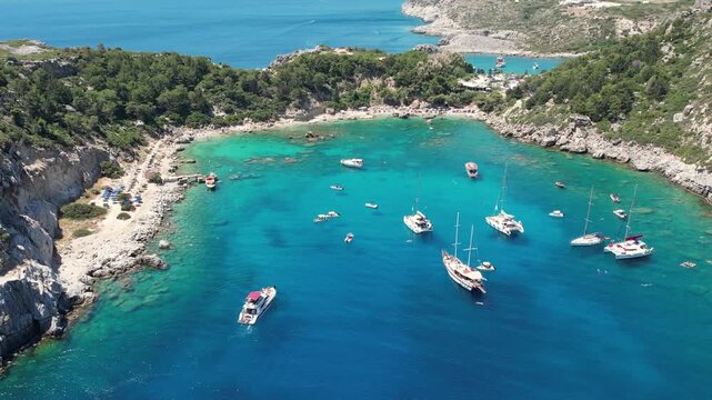 Stunning aerial drone footage of Anthony Quinn Bay on the island of Rhodes, Greece. Bird's-eye view of the turquoise Mediterranean Sea, beautiful sandy beach, rocky coastline and yachts 