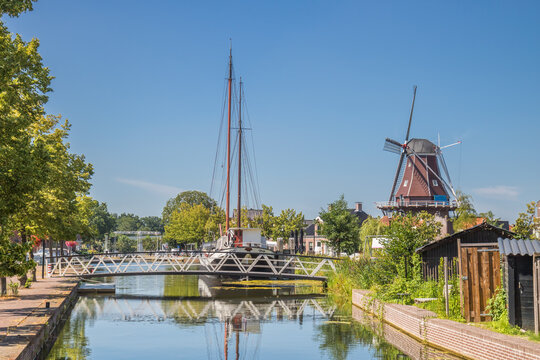 Historic windmill stands beside a scenic canal with a bridge in Meppel, Netherlands
