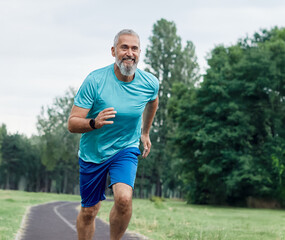Fototapeta premium Smiling active mature middle aged man jogging running in the park