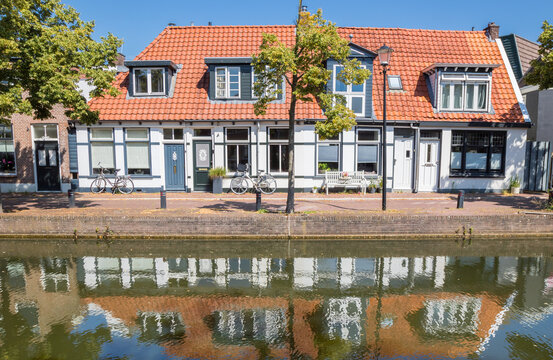 Traditional white canal houses with orange roofs reflect onto the water in Meppel, Netherlands