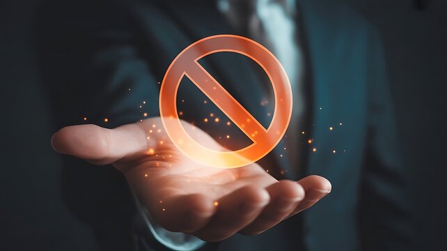 Businessman in a dark suit holding a glowing orange prohibition sign in his open palm with floating sparkles and light particles in a dark setting