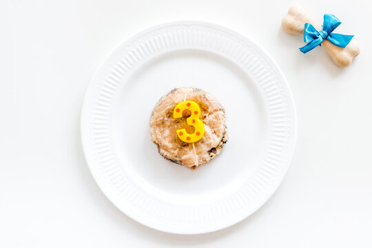 Birthday party for puppy concept. Dog feed, candle in shape of number three, bones on white background top-down