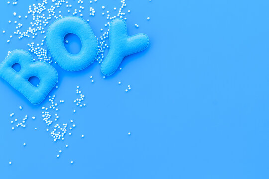 Boy word as decoration for baby shower on blue background top view frame copy space