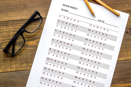 On the exam. Exam sheet, answer near glasses and pencil on dark wooden background top view