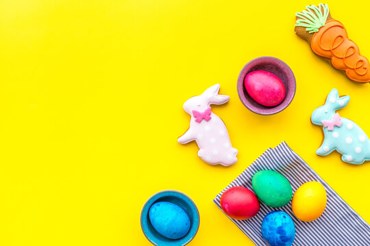 Sweets for celebrate Easter. Gingerbread in shape of easter bunny and easter eggs. Yellow background top view copy space