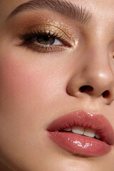 Fototapeta premium Close-up portrait of a woman with glowing golden eyeshadow and glossy nude lips, beauty concept