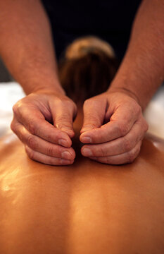 Skilled massage therapist performing a therapeutic treatment on a female clients back, focusing on relaxation and wellness in a serene spa environment with soft lighting