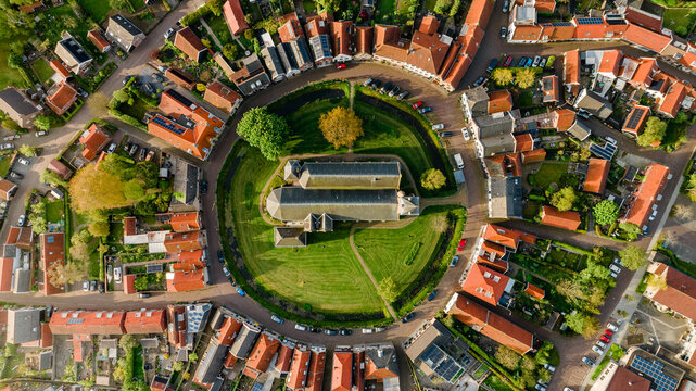 Aerial view of the historic village of Dreischor featuring a central church and circular layout surrounded by residential houses, Dreischor, Zeeland, Netherlands.
