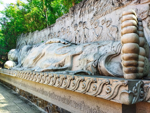 Reclining Buddha entering Nirvana at Long Son Pagoda in Nha Trang, Vietnam, with a relief of 49 disciples behind. Ideal for travel, Buddhism, culture and heritage articles