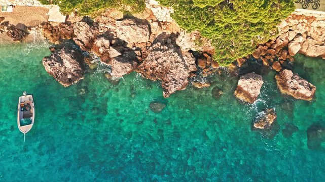 Static top down drone shot of small boat in clear turquoise Adriatic water Croatia