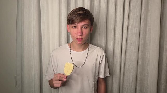 garoto adolescente comendo picol&aacute; de chocolate branco 