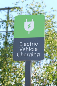 Sign indicating electric vehicle charging station with green colors and clear iconography.
