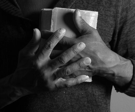 praying to god with hands showing his religious faith with God Caribbean man praying with background with people stock photo stock image