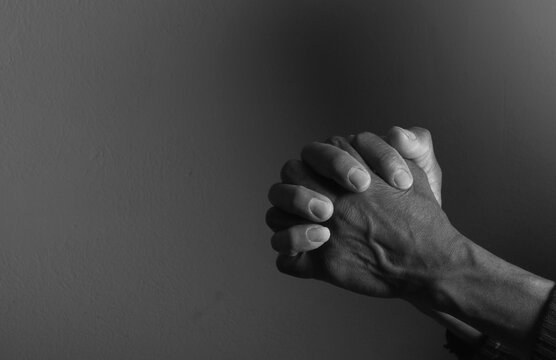 praying to god with hands showing his religious faith with God Caribbean man praying with background with people stock photo stock image