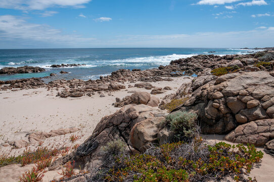 Rugged Western Australian coast with granite rocks, white sand and turquoise waves beneath a blue sky