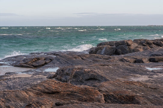 Turquoise waves breaking over granite rocks in Western Australia