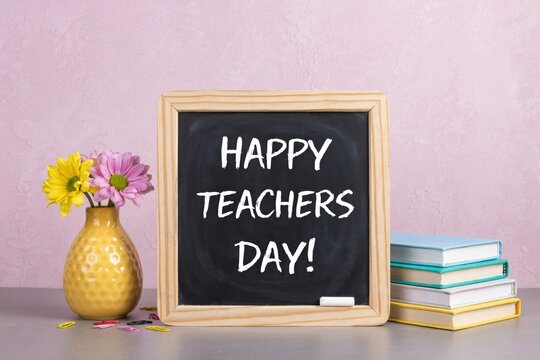 Happy teachers day message on a chalkboard with flowers and books