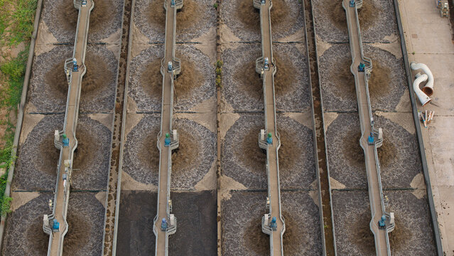 Aerial view of the wastewater treatment plant featuring large aeration tanks with mechanical agitators and industrial infrastructure in Wanlip, England, United Kingdom.