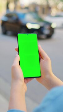 Woman is walking along the street and using smartphone with green screen