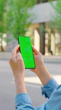 Woman is standing on the street and using smartphone with green screen