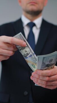 Formally dressed man carelessly throws US Dollar bills towards the camera
