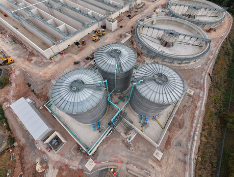 Aerial view of the wastewater treatment plant featuring large circular tanks, industrial infrastructure, and construction activity in Wanlip, England, United Kingdom.