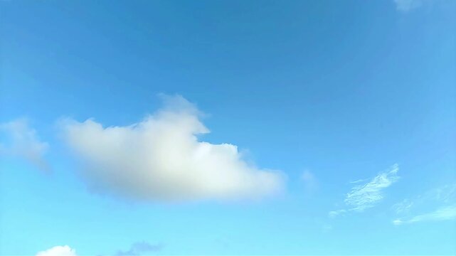 Timelapse of white cumulus cloud floating over vibrant clear blue sky