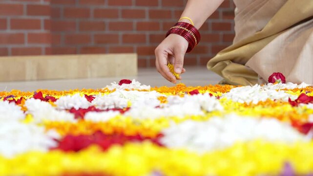 Preparing a floral pookalam kolam with fresh petals for Onam celebration