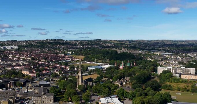 Aerial footage across Bradford in West Yorkshire showing densely packed residential neighbourhoods commercial buildings green spaces and rolling hills stretching across the wider urban landscape
