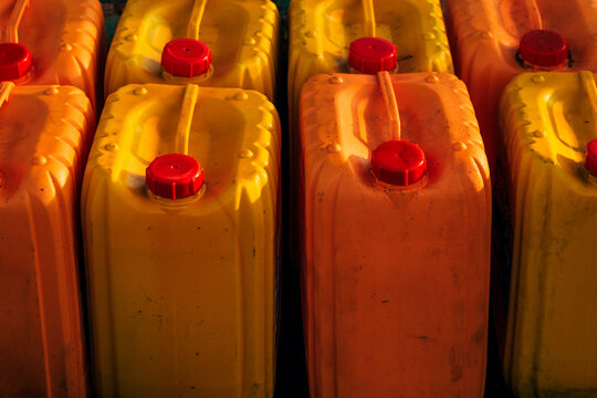 Rows of plastic canisters for fuel, oil, or chemical liquid storage. Concept of industrial supply, fuel reserves, packaging, and resource management.