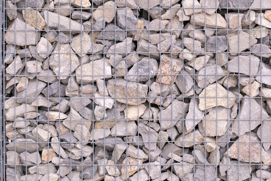 Gabion wall featuring rugged gray stone rocks contained within a durable wire mesh cage, creating a strong and textured background or architectural element
