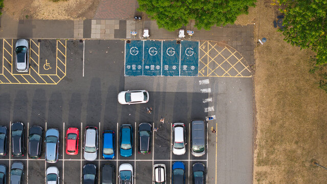 Aerial view of Corley Northbound Services M6 featuring electric vehicle charging zones with blue marked bays and various parked cars in a parking lot in Coventry, England, United Kingdom.