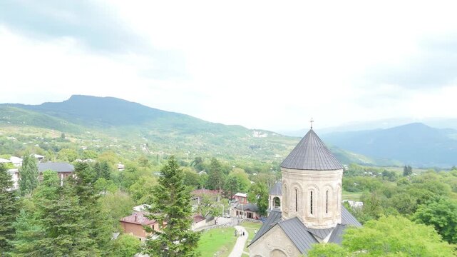 Scenic aerial view of the Nikortsminda church, a Georgian orthodox church in the Racha region, showcasing its unique stone architecture and surrounding landscape