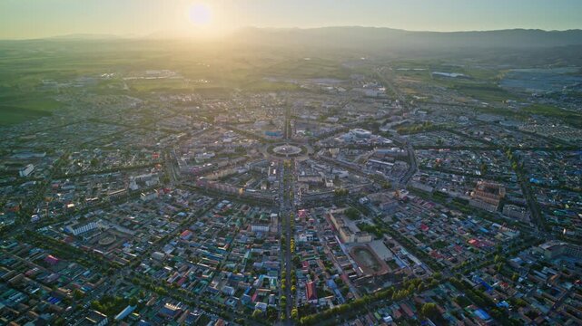 High-Angle Aerial Panoramic View of Tekes Bagua City at Golden Sunset, Ili Unique Bagua I-Ching Geometric Layout, Warm Twilight, Mountain Range and Horizon in Xinjiang