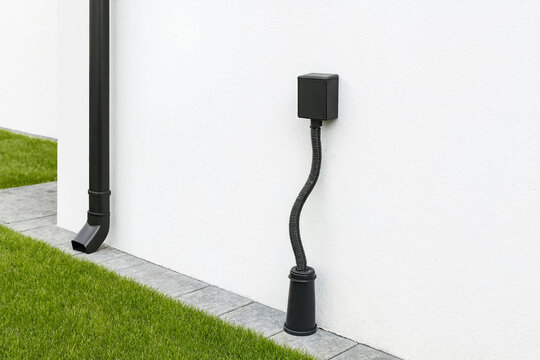 Black electrical utility box mounted on a modern white exterior wall with conduit