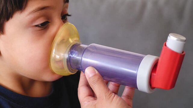 Child inhales respiratory medication through metered-dose inhaler spacer mask