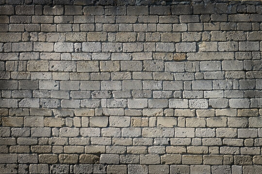 Close-up of an aged gray brick wall with rough stone texture, irregular blocks and weathered surfaces. Rustic masonry background with a timeless architectural character