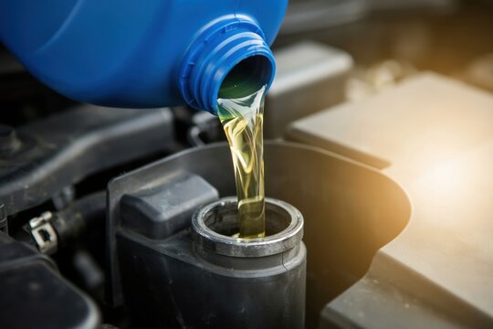 Pouring fresh motor oil into a car engine during a routine maintenance service
