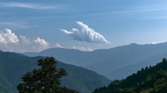 A whimsical cloud shaped like a fish glides above layered mountain ranges under a clear blue sky
