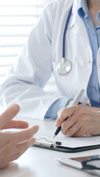 Medical professional filling out prescription, consulting patient about health concerns during clinical consultation. Medicine and health care concept