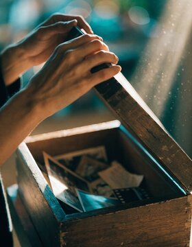 A serene moment of discovery hands gently opening an old wooden memory box filled with photographs and keepsakes connecting past and present in a cinematic setting