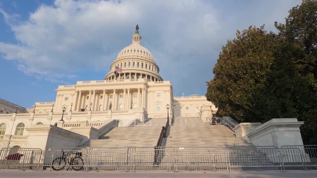 United states capitol building in washington d.C. Panning up to reveal the iconic dome, the east front facade, the senate chamber wing, and the waving american flag