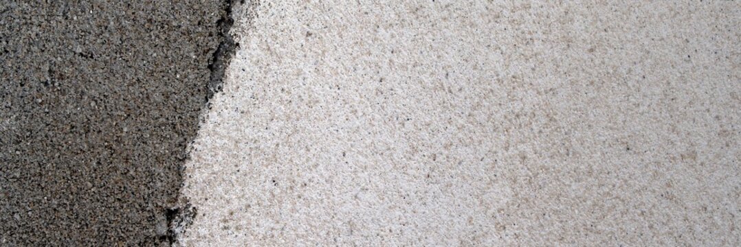 Rough concrete wall showing two distinct textures and shades of grey