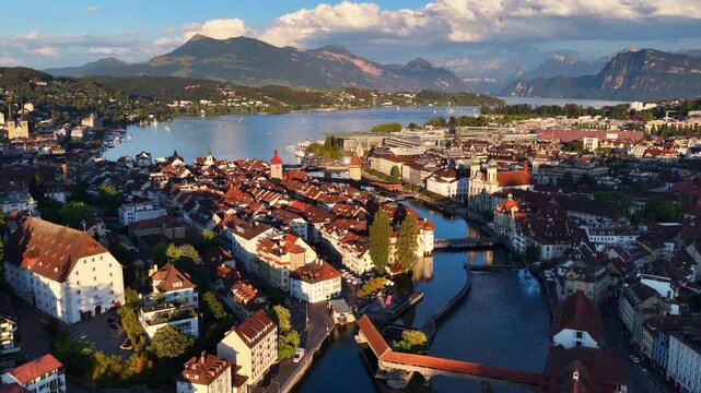drone orbiting shot of Lucerne old town with lake Lucerne, medieval Chapel bridge and Swiss Alps, travel in Switzerland, establishing aerial cityscape of Luzern