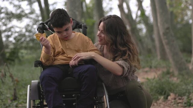 Mother assisting son with cerebral palsy in wheelchair in a park