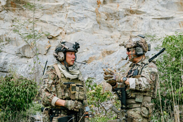 Naklejka premium Two focused outdoor soldiers jungle soldiers soldiers on duty communicate with intense concentration while planning tactical operation