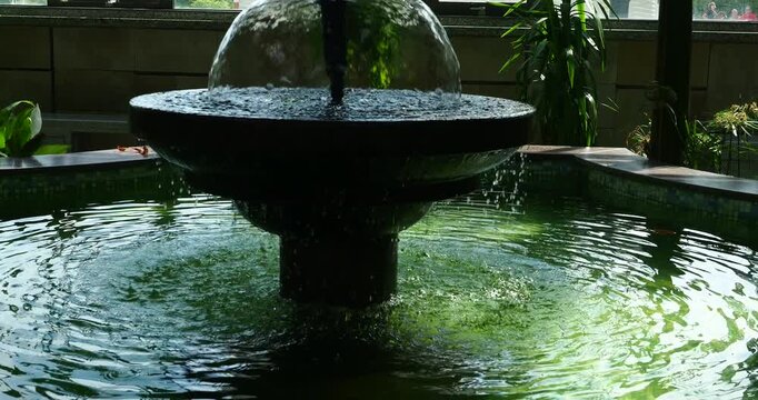 Fountain in Moszna Castle Indoor Garden with Slow Zoom In - Slow zoom-in toward a decorative fountain with flowing water in the indoor garden of Moszna Castle in Poland. 