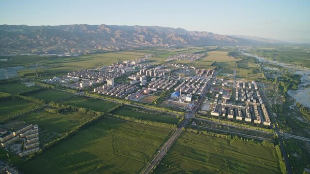 High-Angle Aerial View of Tekes River and Tekes River Bridge at Sunset in Ili Warm Evening Twilight, Mountain Range, Rural Farmlands and Open Plain Landscape in Xinjiang