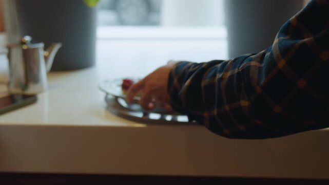 Close up of person arranging plates with food on them. hand places green ceramic dishes holding cake and sandwich onto silver serving trays then positions tray neatly at white countertop